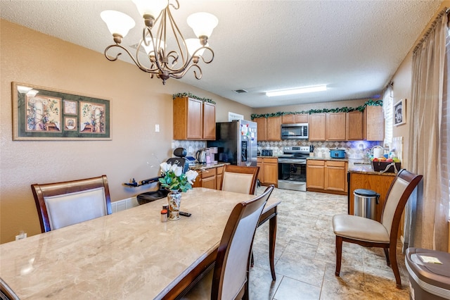 dining room featuring an inviting chandelier, visible vents, and a textured ceiling