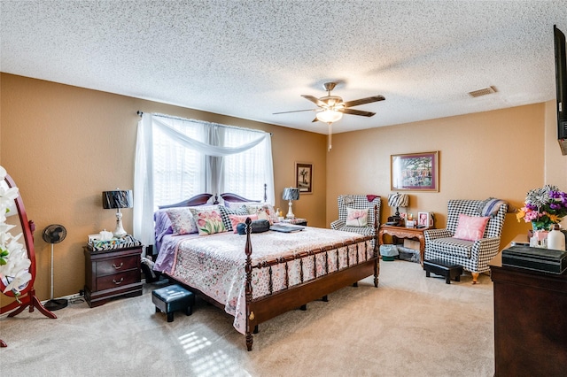 bedroom featuring light carpet, a textured ceiling, visible vents, and a ceiling fan