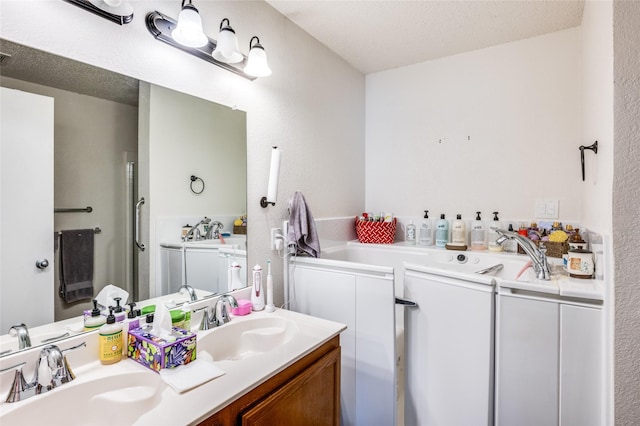 bathroom with double vanity, a garden tub, a textured ceiling, and a sink