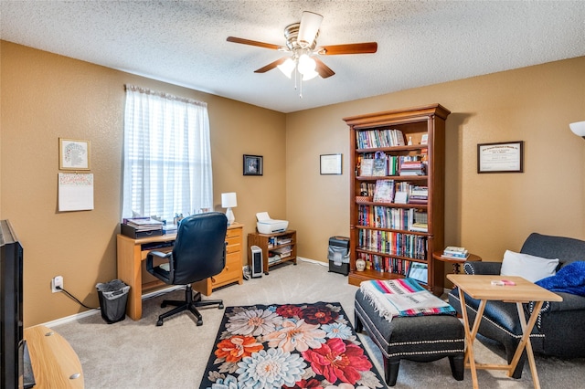 home office with a textured ceiling, ceiling fan, baseboards, and light colored carpet