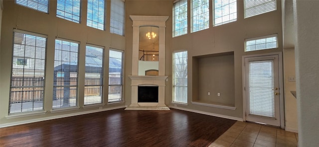 unfurnished living room with hardwood / wood-style floors, a wealth of natural light, and a high ceiling