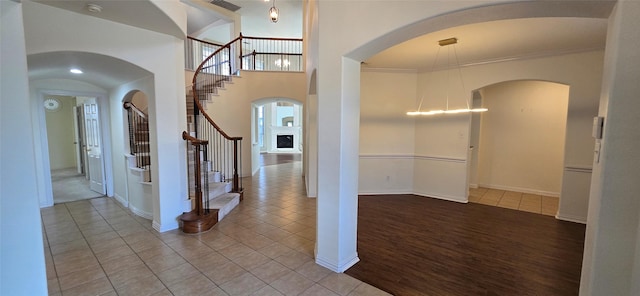 entryway with hardwood / wood-style flooring, crown molding, and a high ceiling