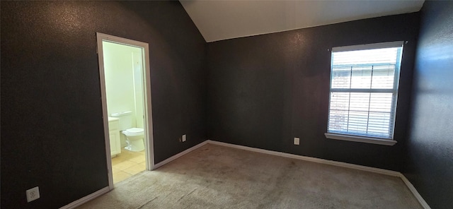 spare room featuring light carpet and vaulted ceiling