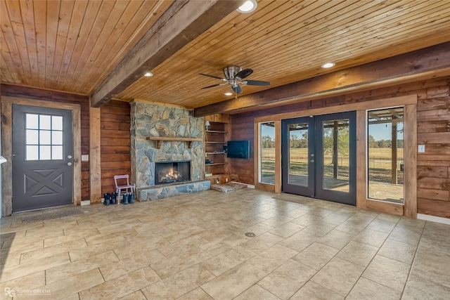 unfurnished living room featuring a fireplace, beam ceiling, wooden walls, and wooden ceiling