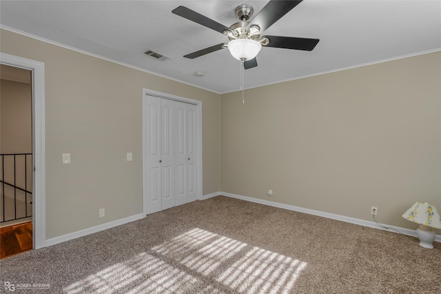 unfurnished bedroom featuring ornamental molding, a closet, ceiling fan, and carpet