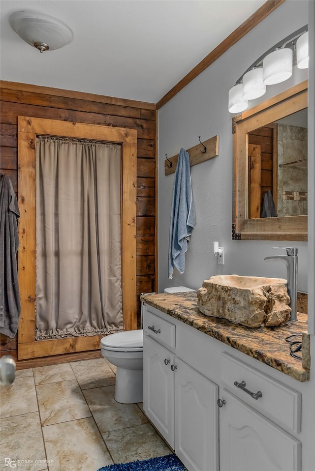 bathroom with vanity, ornamental molding, wooden walls, and toilet