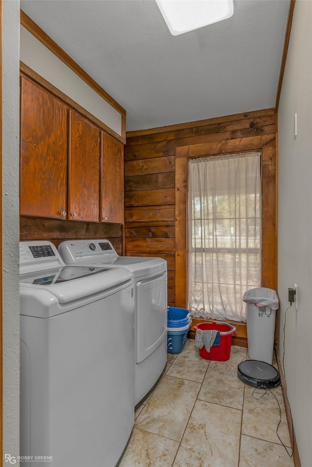 washroom with cabinets, ornamental molding, washer and dryer, and wood walls