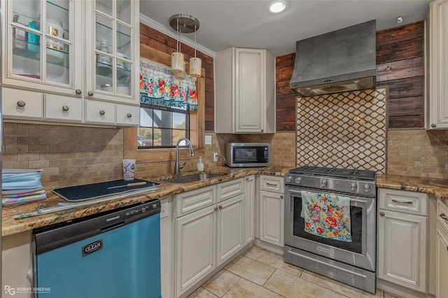 kitchen featuring sink, appliances with stainless steel finishes, white cabinetry, custom range hood, and decorative light fixtures