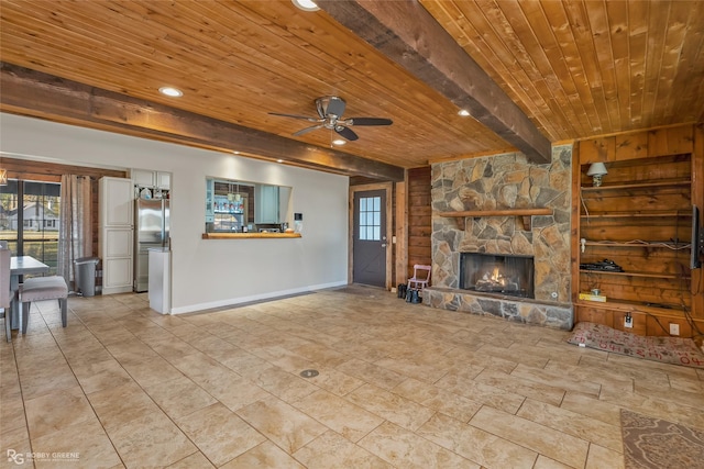 unfurnished living room with ceiling fan, beam ceiling, a fireplace, wooden ceiling, and wood walls