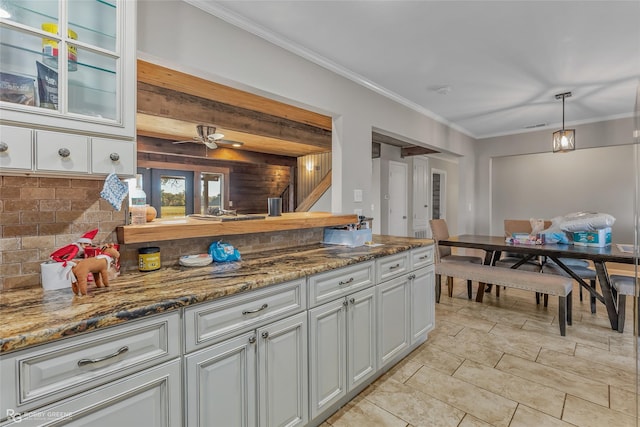 kitchen with crown molding, white cabinetry, backsplash, hanging light fixtures, and dark stone counters