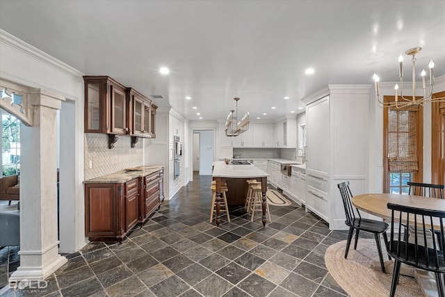 kitchen with a kitchen bar, decorative backsplash, a kitchen island, and ornamental molding