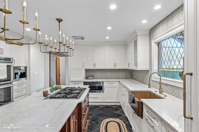 kitchen featuring light stone countertops, decorative light fixtures, stainless steel appliances, and white cabinetry