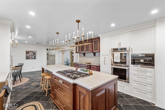 kitchen with a center island, hanging light fixtures, appliances with stainless steel finishes, a kitchen breakfast bar, and white cabinets