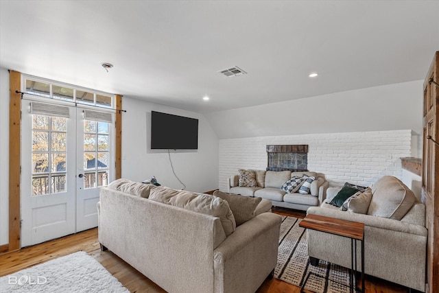 living room featuring light hardwood / wood-style floors, lofted ceiling, and french doors