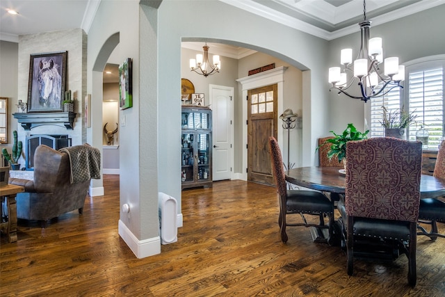 dining space featuring dark hardwood / wood-style floors, crown molding, a fireplace, and an inviting chandelier