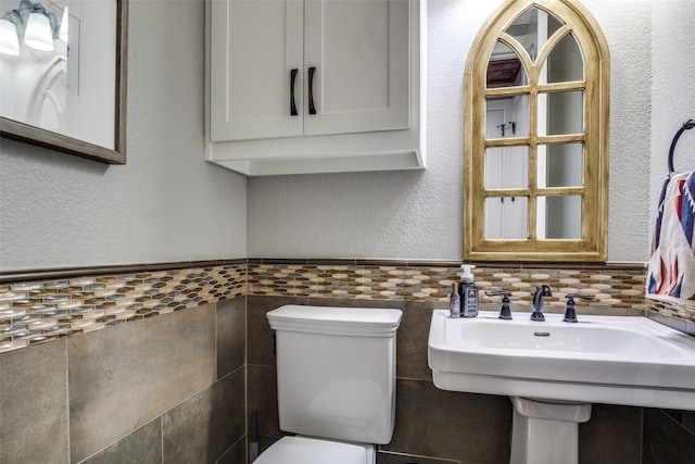 bathroom featuring toilet and tile walls