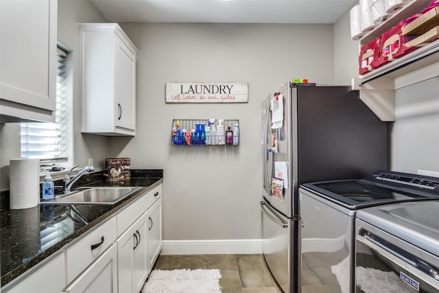 kitchen featuring white cabinetry, sink, dark stone countertops, light tile patterned floors, and washer and dryer