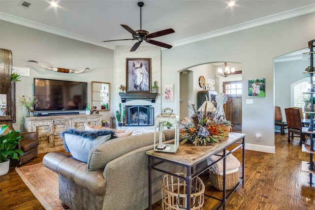 living room featuring a fireplace, dark wood-type flooring, ceiling fan with notable chandelier, and ornamental molding