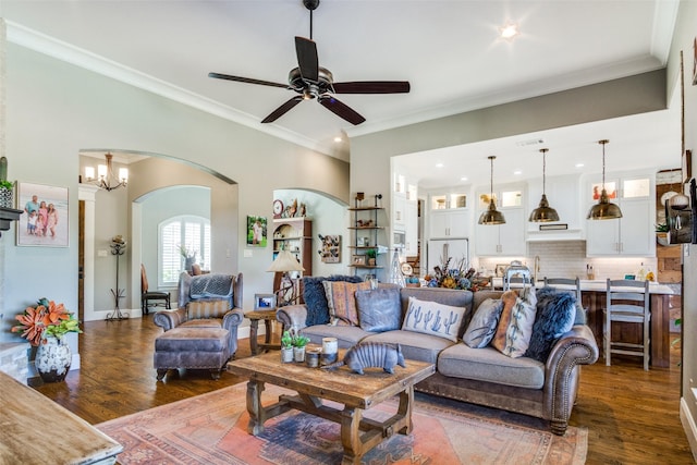 living room featuring crown molding, dark wood-type flooring, and ceiling fan with notable chandelier