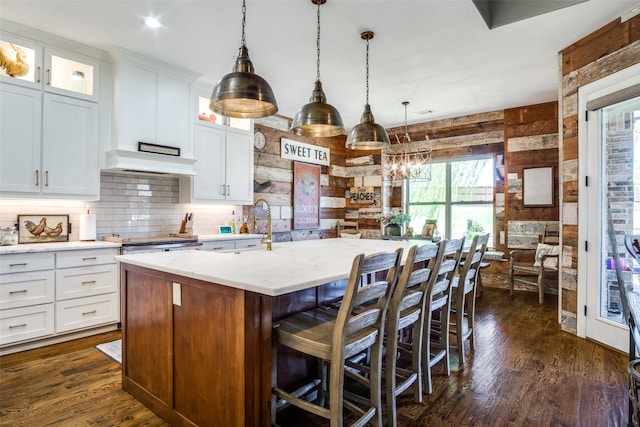 kitchen featuring white cabinetry, a kitchen island with sink, and pendant lighting