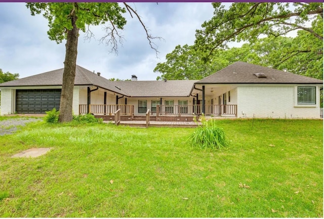 rear view of house featuring a garage, a yard, and a deck