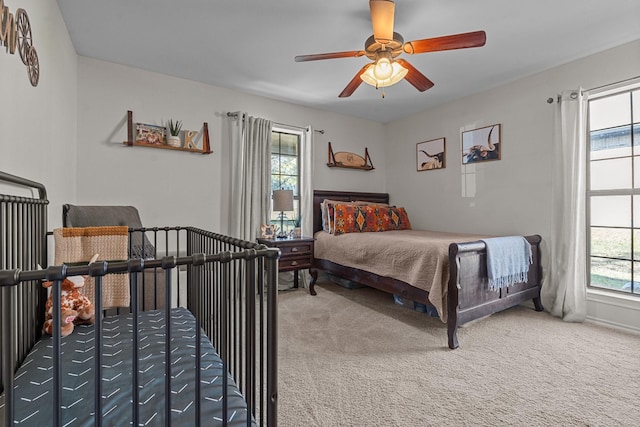 carpeted bedroom featuring multiple windows and ceiling fan