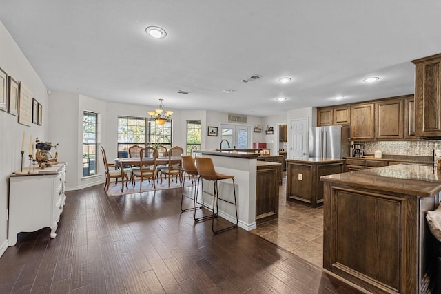 kitchen with decorative light fixtures, a kitchen island, dark hardwood / wood-style flooring, stainless steel refrigerator, and a chandelier