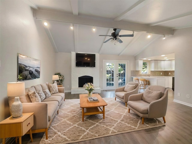 living room featuring ceiling fan, a fireplace, lofted ceiling with beams, and light wood-type flooring