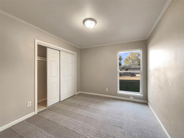 unfurnished bedroom featuring crown molding, a closet, and carpet