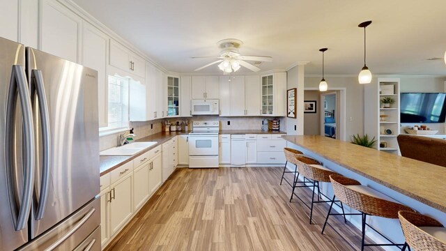 kitchen with decorative light fixtures, white cabinetry, white appliances, and sink