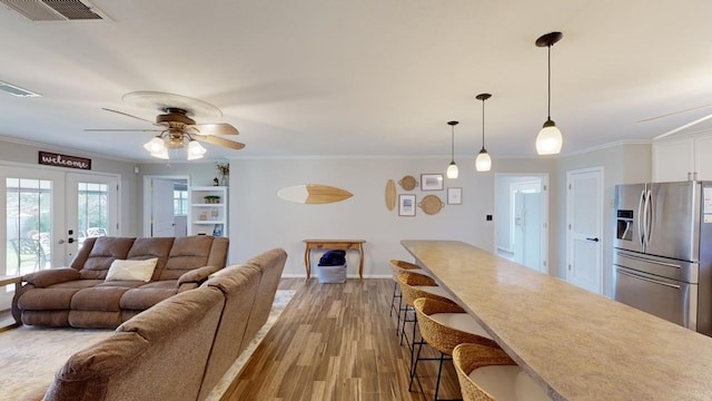 living room with french doors, light hardwood / wood-style floors, ceiling fan, and ornamental molding