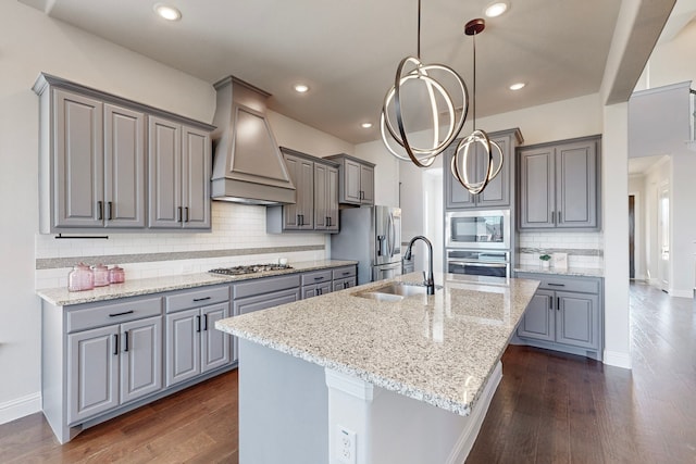 kitchen with a kitchen island with sink, dark hardwood / wood-style flooring, stainless steel appliances, and custom exhaust hood