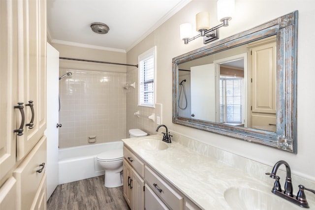 full bathroom featuring vanity, tiled shower / bath, hardwood / wood-style flooring, toilet, and ornamental molding