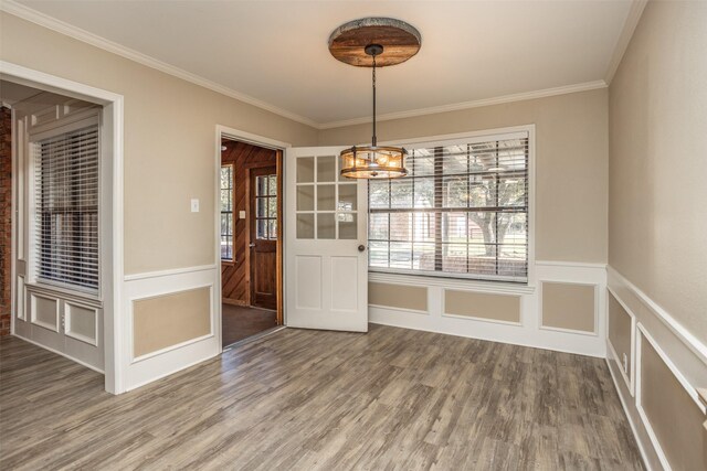 unfurnished dining area with hardwood / wood-style floors, ornamental molding, and an inviting chandelier