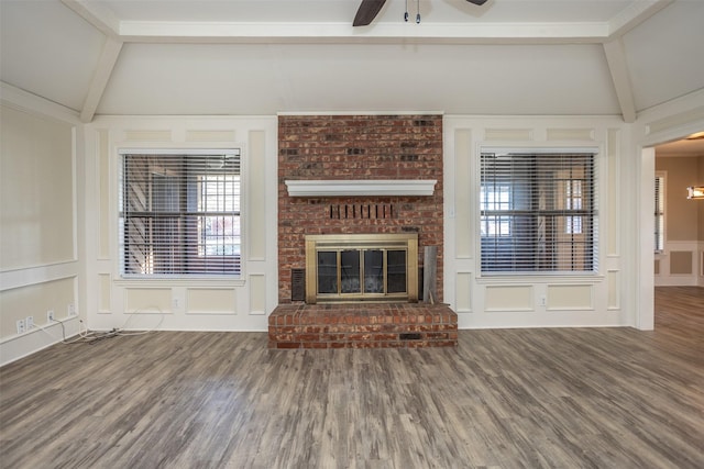 unfurnished living room with hardwood / wood-style floors, lofted ceiling with beams, ceiling fan, and a brick fireplace