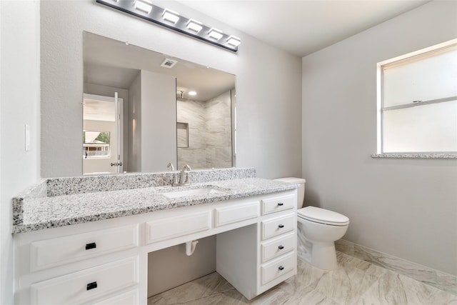 bathroom with vanity, toilet, and tiled shower