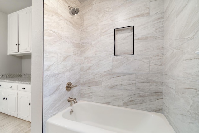 bathroom featuring hardwood / wood-style flooring, tiled shower / bath combo, and vanity