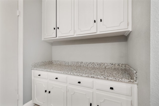 kitchen featuring light stone counters and white cabinetry