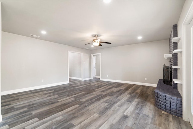 unfurnished living room featuring a brick fireplace, ceiling fan, and dark wood-type flooring