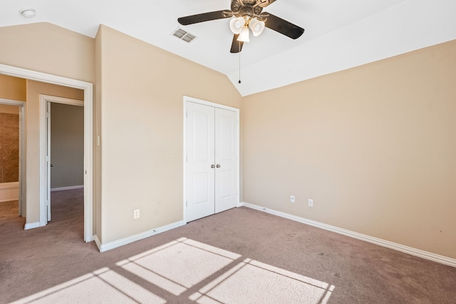 unfurnished bedroom featuring lofted ceiling, light colored carpet, ceiling fan, and a closet