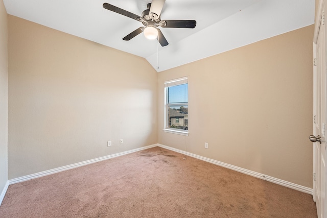 carpeted spare room featuring vaulted ceiling and ceiling fan