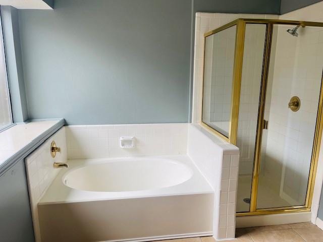 bathroom with a garden tub, a shower stall, and tile patterned floors