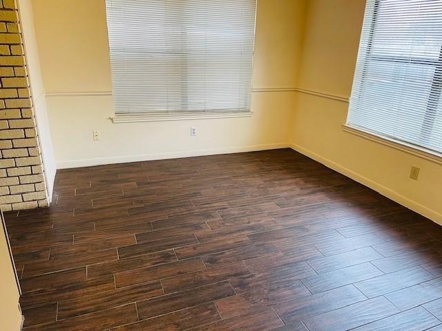 empty room featuring baseboards and dark wood-type flooring