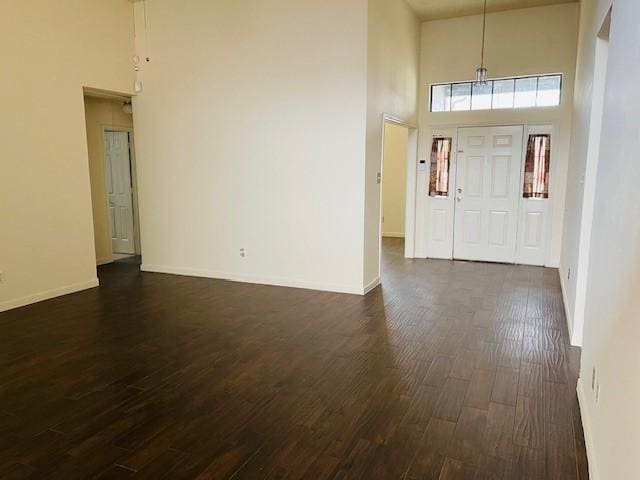 entryway featuring a high ceiling, baseboards, and dark wood finished floors