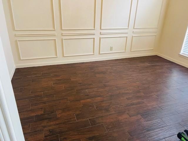 interior space with baseboards, dark wood finished floors, and a decorative wall