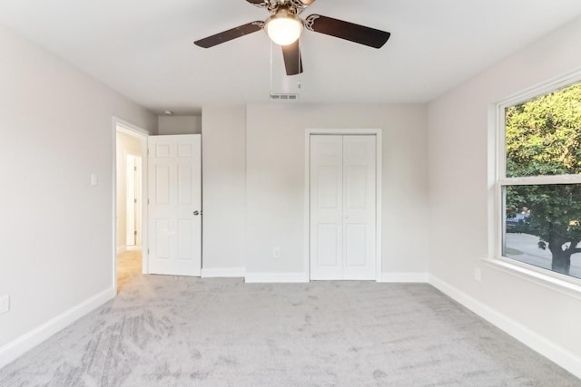 unfurnished bedroom featuring ceiling fan, a closet, and light carpet