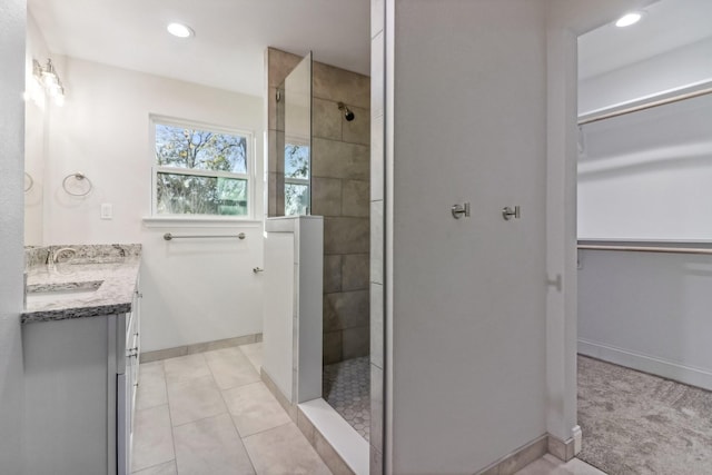 bathroom with a tile shower, vanity, and tile patterned floors