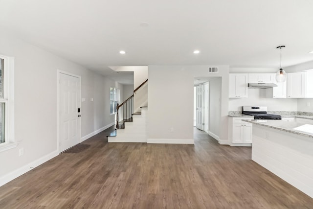 kitchen featuring pendant lighting, dark wood-type flooring, white cabinetry, stainless steel range, and light stone countertops