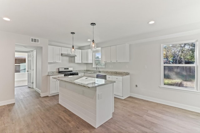 kitchen featuring white cabinetry, gas range gas stove, a kitchen island, and light wood-type flooring