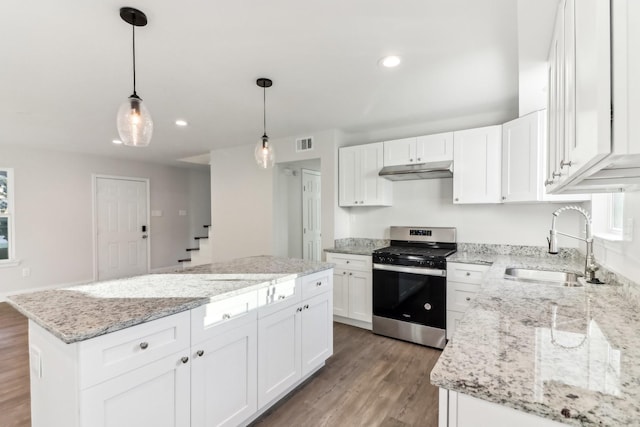 kitchen featuring white cabinets, sink, hanging light fixtures, stainless steel range, and a kitchen island